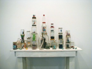 “Le Roi de Bâton,” 1991, glass bottles and jars with plastic and metal lids, found objects, found table. Image: Blaffer Art Museum.