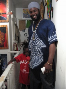 Lyles with one of his five-year-old twins stands in the upstairs hallway crowded with art.