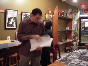 Joe Boruchow, before the opening, laying out free copies of his posters