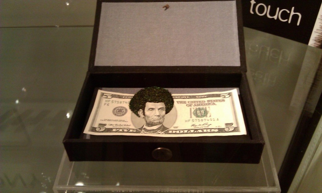 Sonya Clark, Afro Abe (Peacock), 2010, 1 of 44, only one with feathers; five dollar bill with stitched peacock feathers, 4 x 6 inches