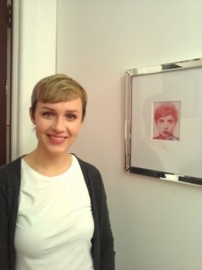 Erica Prince, in her studio, posing with a digital portrait that merges her features with those of her boyfriend.