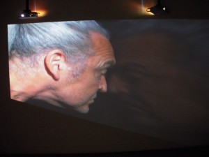Gary Hill, video piece in which he pushes his body against a glass wall. The audio hums at an alarming decibel level.