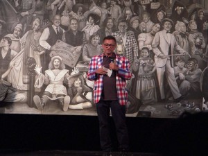 Navin Rawanchaikul, speaking in front of his mural at Plays and Players Theater