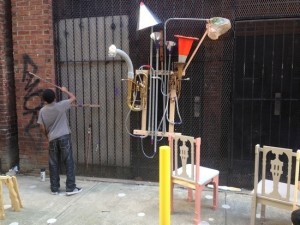 A youth playing the found material instrument by Steve parker and Jebney Lewis