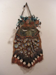 Gretchen Shannon, Protection Mask, plaster cast, hand painted, hand sewn, collage, burlap, pheasant feathers, cowrie shells, beads, cut steel and copper