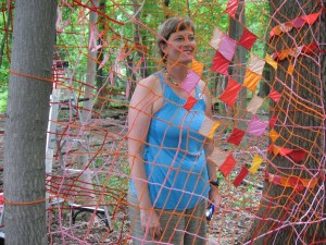 Abington Curator Sue Spain, standing in Caroline Lathan Staffel's piece in the woods.