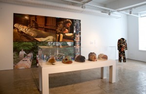 New American Voices, Tommy Joseph installation shot from left to right, totem pole carving mural, White Raven Helmet, Rockfish Helmet, Raven Helmet, Human Helmet, Eagle Helmet, and Eagle Wolf Suit Photo: Will Brown
